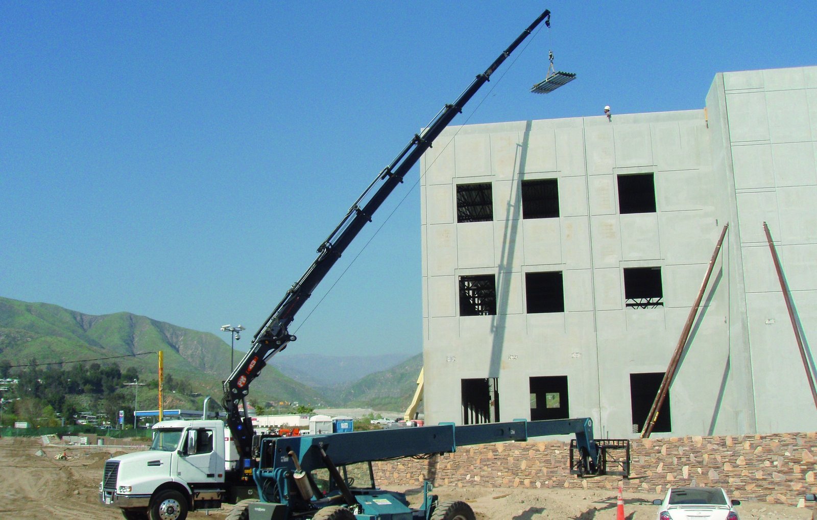 PM knuckle boom crane setting a panel on a four story precast building